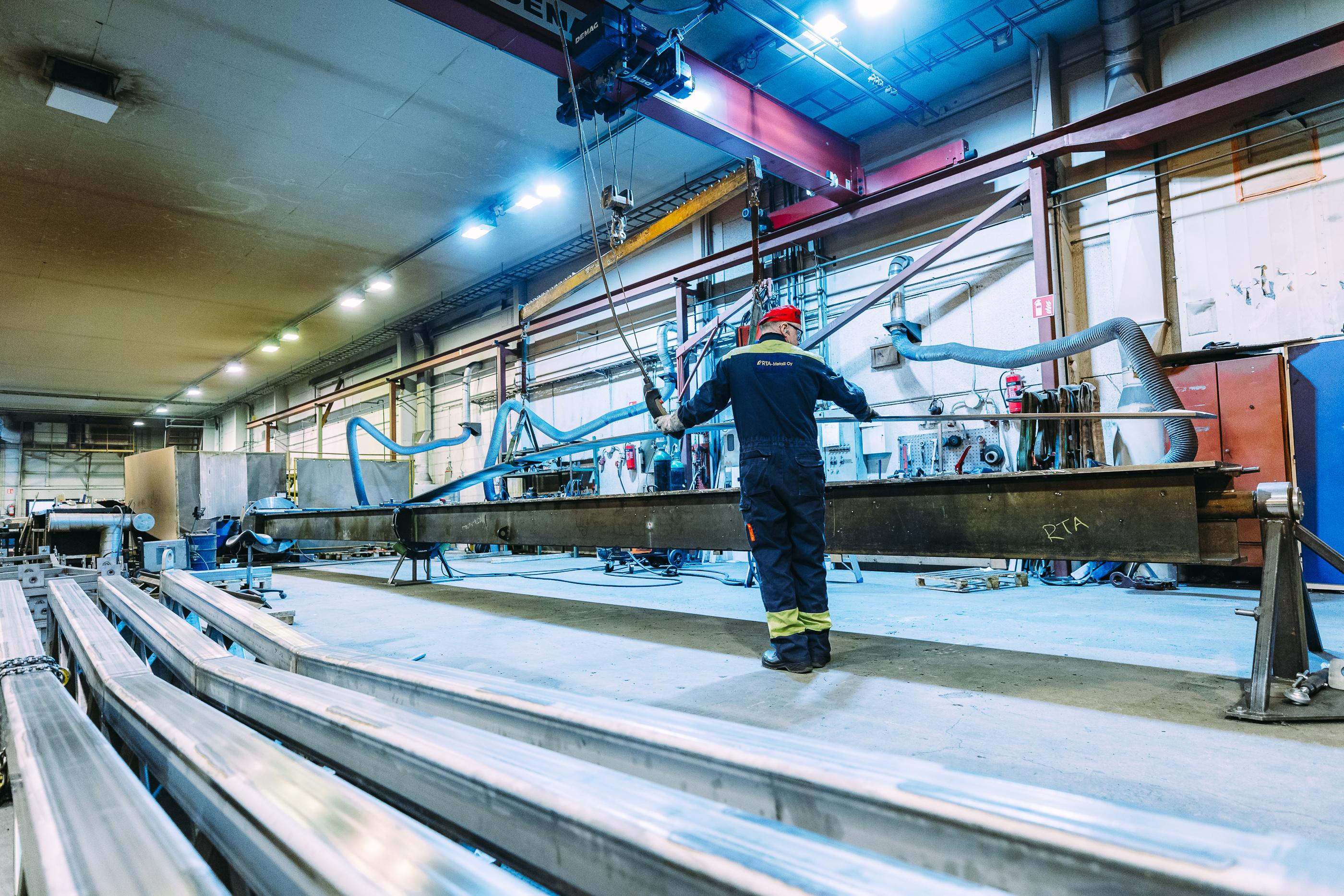 Teollisuushallin sis&auml;tilat, joissa metallity&ouml;ntekij&auml; ohjaa suurta ter&auml;srakennetta nosturilla. Moderni konepajaymp&auml;rist&ouml; mahdollistaa tarkkuutta vaativat metallity&ouml;t ja kokoonpanopalvelut.